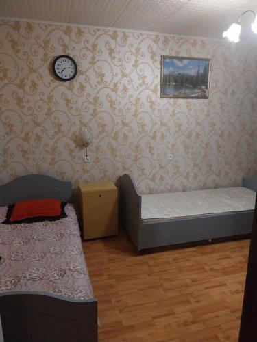 a room with two beds and a clock on the wall at Buto nuama in Mažeikiai