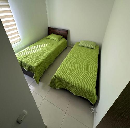 dos camas sentadas una al lado de la otra en un dormitorio en Apartamento en conjunto con piscina, en Ibagué