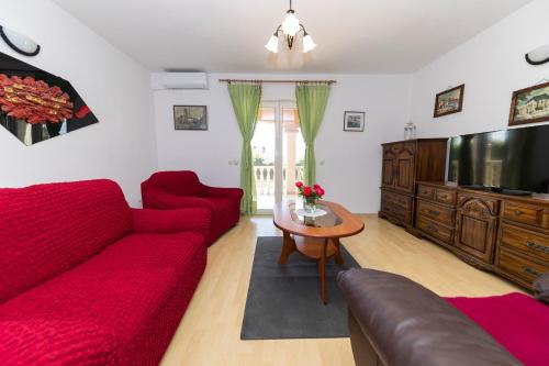 a living room with a red couch and a tv at Kuća za odmor Pixie in Vrsi