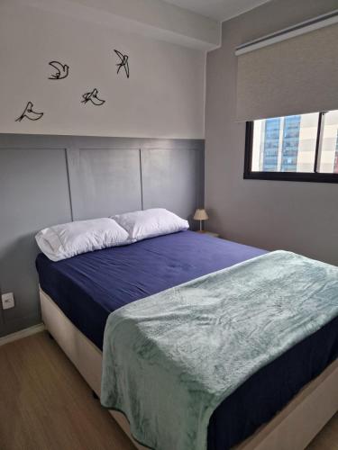 a bedroom with a bed with blue sheets and a window at Studio Liberdade in São Paulo