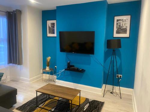 a living room with a blue wall with a flat screen tv at The Sailsbury Snug in Southend-on-Sea