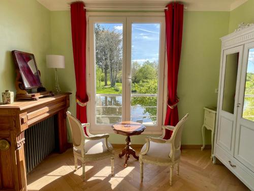 une pièce avec une table, des chaises et une fenêtre dans l'établissement Le Moulin de Bury, Maison de campagne au bord de la rivière à 13 kms au Sud de Rennes, à Chavagne