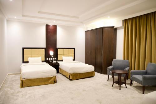 um quarto de hotel com duas camas e uma cadeira em فندق أصداء الراحة Asdaa Alraha Hotel em Jidá