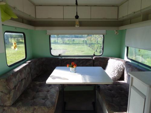 uma mesa na parte de trás de um comboio com duas janelas em Caravan Vlinder em Rouveen