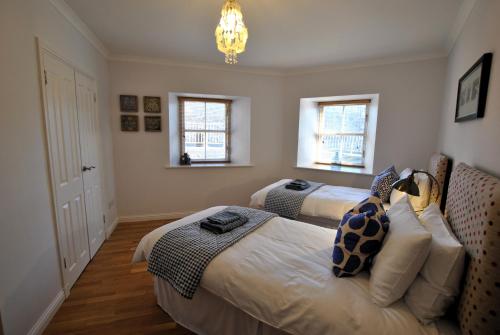 a bedroom with two beds and a chandelier at Coorie Cottage- stylish townhouse Anstruther in Anstruther