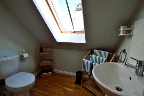 a bathroom with a toilet and a sink and a skylight at Coorie Cottage- stylish townhouse Anstruther in Anstruther