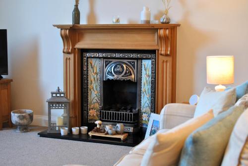a living room with a fireplace and a couch at Kirkmay House Apartment in Crail