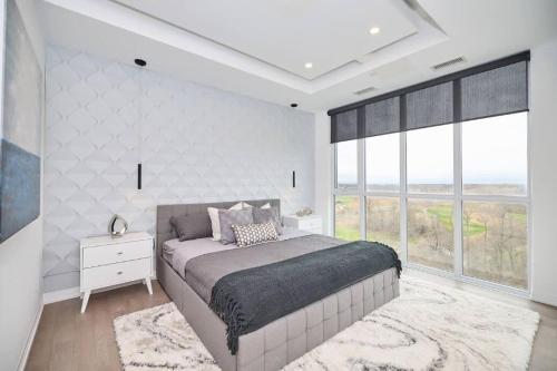 um quarto com uma cama grande e janelas grandes em Penthouse on the Green em Cataratas do Niágara