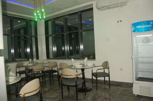 a group of tables and chairs in a room with windows at HOTEL DEE NARIOS in Uyo