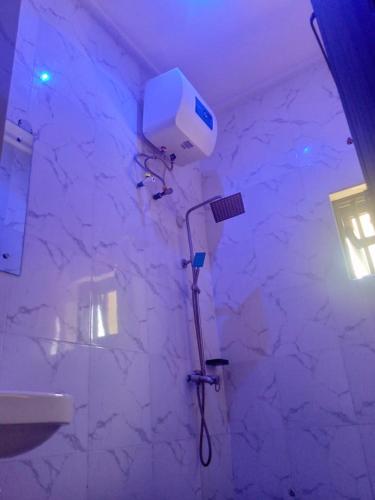 a shower in a bathroom with a white marble wall at HOTEL DEE NARIOS in Uyo