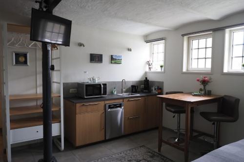 a kitchen with a sink and a microwave and a table at Boerderij de Enkhoeve in Laag-Soeren