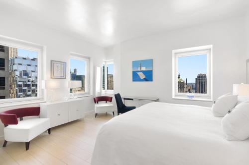 um quarto branco com uma grande cama branca e janelas em Luxury 4 Bedroom Apartment near Times Square NYC em Nova York