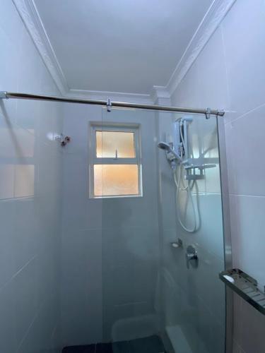 uma casa de banho com uma cabina de duche em vidro e uma janela. em Todas Hotel em Kiambu