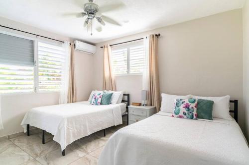 een slaapkamer met 2 bedden en een plafondventilator bij Relax Home Plenty Space Near The Airport - 4min in Aguadilla