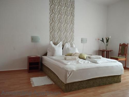 a bedroom with a large bed with white sheets at Bányai Apartman in Gyula