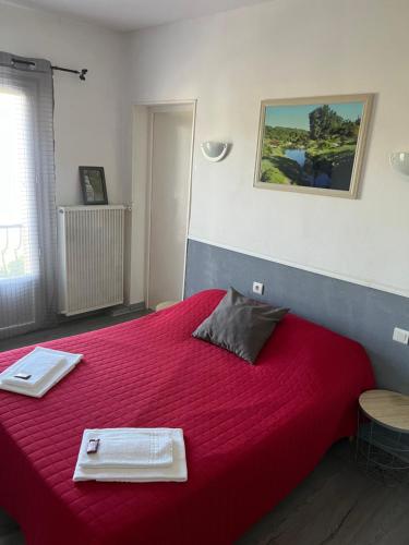 ein Schlafzimmer mit einem großen roten Bett mit zwei Platten darauf in der Unterkunft Hôtel Restaurant Douce France in Saint Alban Auriolles