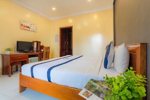 a bedroom with a bed and a desk and a television at Khách Sạn Hạnh Long in Ho Chi Minh City