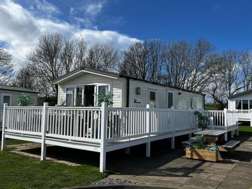 a small white house with a white fence at Sandy Bay Caravan Getaway in Newbiggin-by-the-Sea