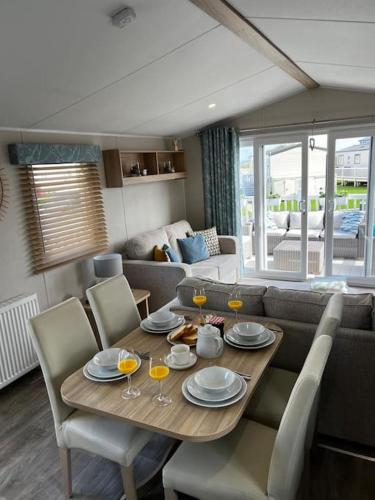 a dining room table with chairs and a living room at Sandy Bay Caravan Getaway in Newbiggin-by-the-Sea