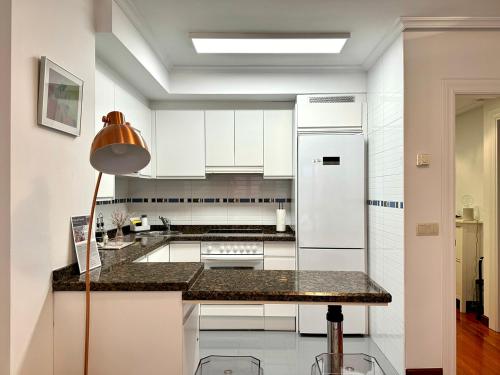 uma cozinha com armários brancos e um balcão preto em Apartamento "Balcón del Parchís" a 200 metros de la playa em Gijón