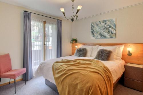 1 dormitorio con 1 cama, 1 silla y 1 ventana en Penthouse With Sunny Balcony And Sauna, en Champéry