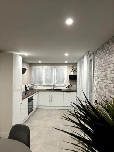 une cuisine avec des placards blancs et un mur en briques dans l'établissement Appartement cosy 90m²/ 6 personnes, à Ternay
