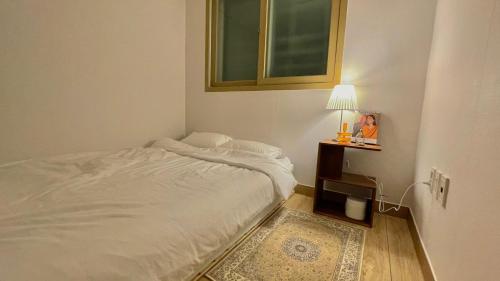 a bedroom with a white bed and a table with a lamp at Ansik in Busan