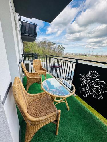 a balcony with two chairs and a glass table at Apartamenty Dębowa 10 in Milicz