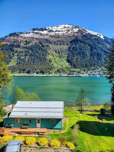 a house next to a lake with a snow covered mountain at Ocean and Mountain View Home, near Downtown Juneau in Juneau
