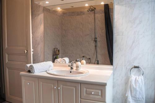 une salle de bain avec un lavabo et un grand miroir dans l'établissement Waterfront Manoir near Paris, Champagne and Disney, à La Ferté-sous-Jouarre