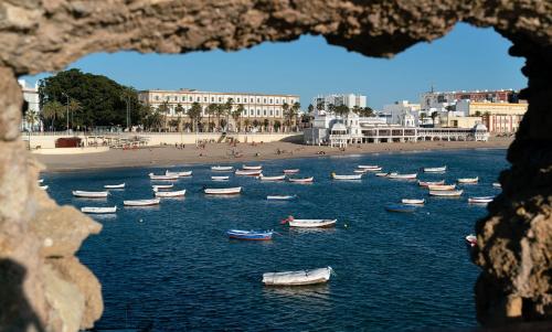 a group of boats in the water near a beach at El Faro del Manteca in Cádiz