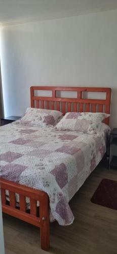 a bed with a quilt on it in a bedroom at Condominio en La Florida in Santiago