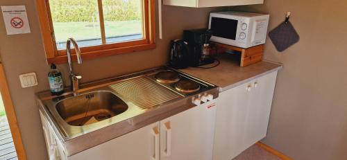 a kitchen with a sink and a microwave at Ängdala Camping på Österlen in Kivik