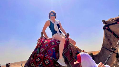 a woman riding on the back of an elephant in the desert at Locanda pyramids view in Cairo