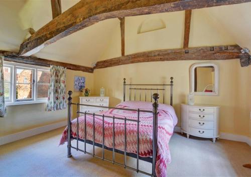 a bedroom with a bed and two dressers and windows at Half Moon Inn in Aylsham