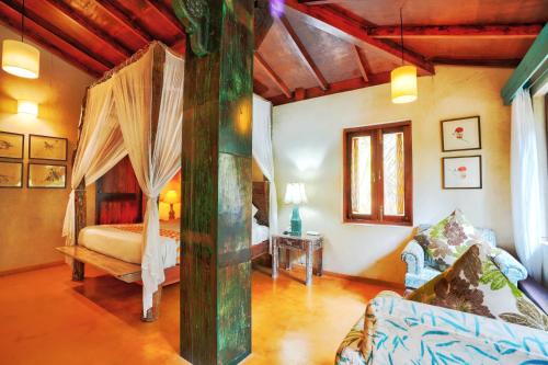 una camera con letto a baldacchino e divano di Sovi - Luxury apartments with pool near Mandrem beach north Goa a Mandrem