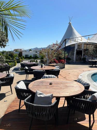 a patio with tables and chairs and a pool at Penthouse i sjøkanten på Dejablue in Kérynia