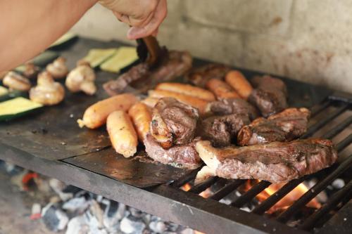 a person cooking meat and vegetables on a grill at Hotel Bania travels in Guatapé