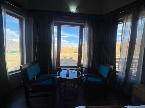 una stanza con due sedie e un tavolo e due finestre di Guza Ethnic Resort a Leh