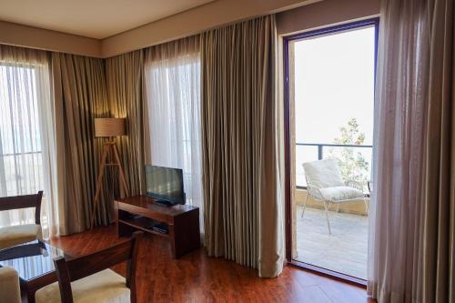 a hotel room with a television and a balcony at Luxury Dreamland Oasis Apartments in Chakvi