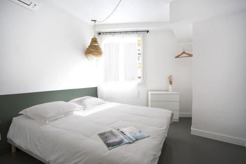 - une chambre avec un lit blanc et 2 livres dans l'établissement Appartement 3 pièces / proche plage / centre / clim, à Antibes