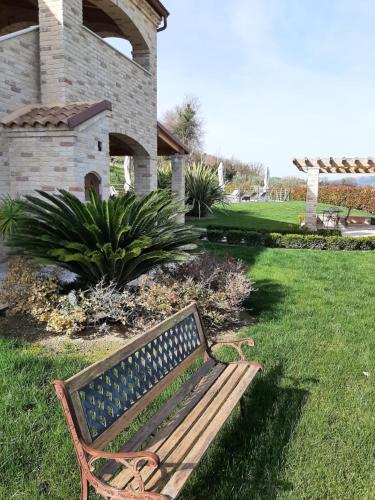 a wooden bench sitting in the grass in a yard at B&B CasalFarano in Cupra Marittima