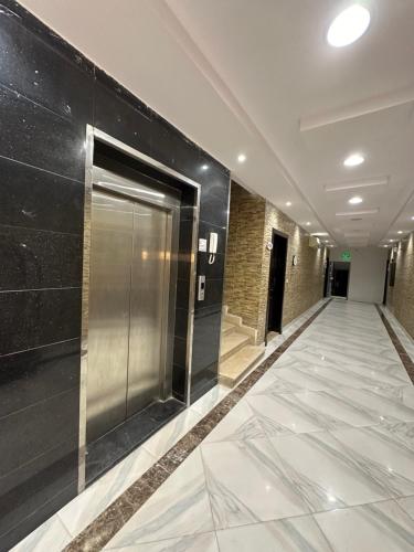un couloir avec une porte métallique dans un bâtiment dans l'établissement Dorat alsafaa, à Hafr Al Baten