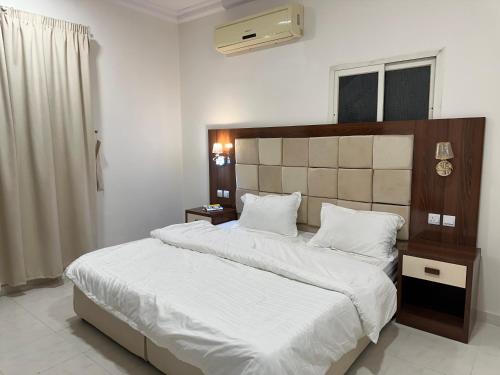 una camera da letto con un grande letto con lenzuola bianche di Dorat alsafaa a Hafr Al Baten