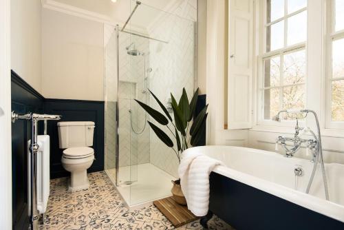 a bathroom with a bath tub and a toilet at Cairnbank House & Garden Apartment in Duns