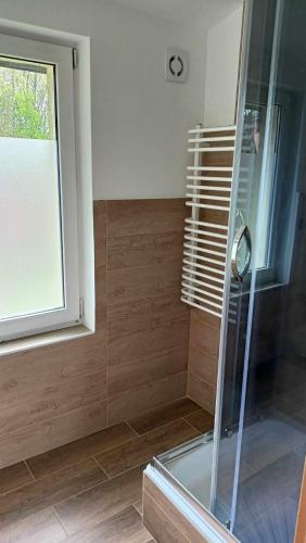 a shower with a glass door and a window at Oberża KNIEJÓWKA in Załom