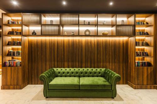 a green couch in a room with a book shelf at La Piscine Art Hotel, Philian Hotels and Resorts in Skiathos Town