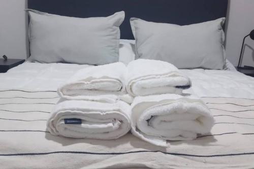 una pila de toallas blancas en una cama en Alojamiento de lujo! G&A Rent! (101) en Ezeiza