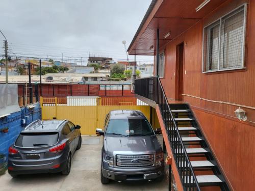 zwei Autos auf einem Parkplatz neben einem Gebäude geparkt in der Unterkunft Hostal aleja in Caldera
