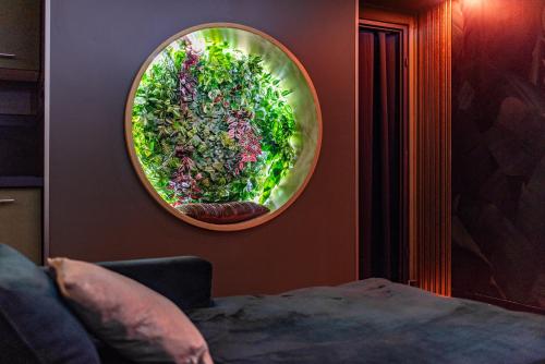 a round mirror hanging on a wall with greens at L’Insolite, Spa Privatif (Appartement Jacuzzi) in Toulouse